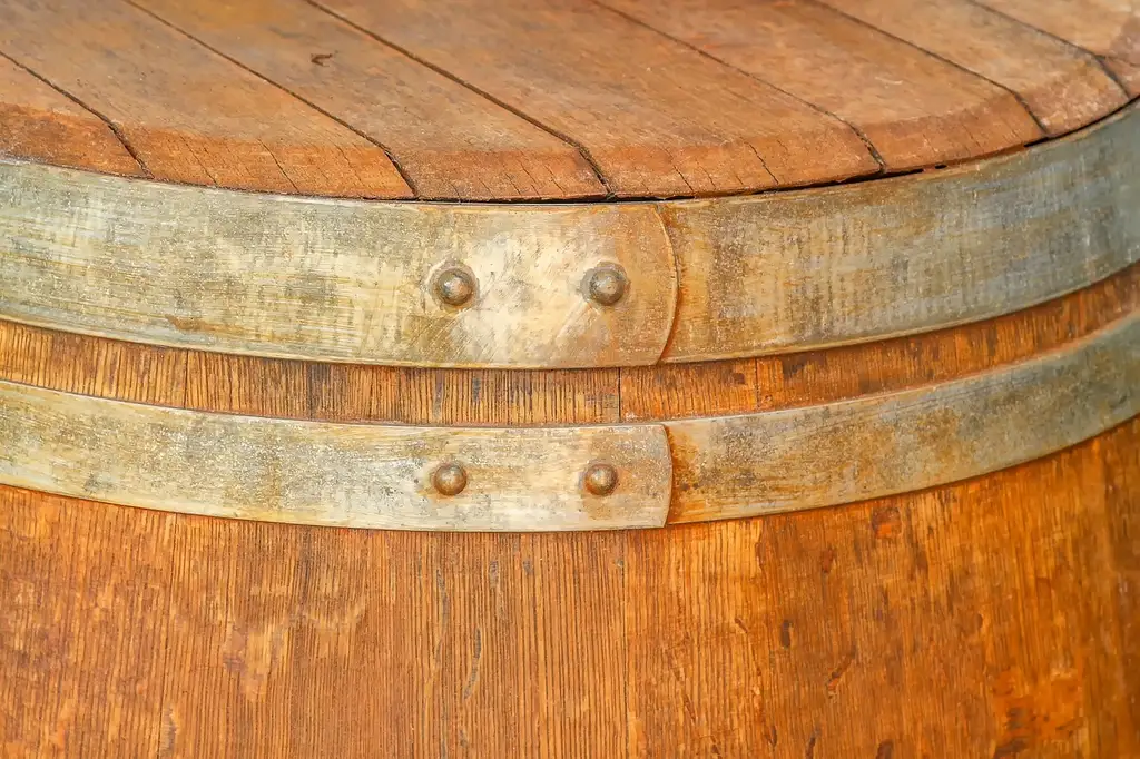 Rain barrel on a stand feeding drip tubing into a vegetable garden