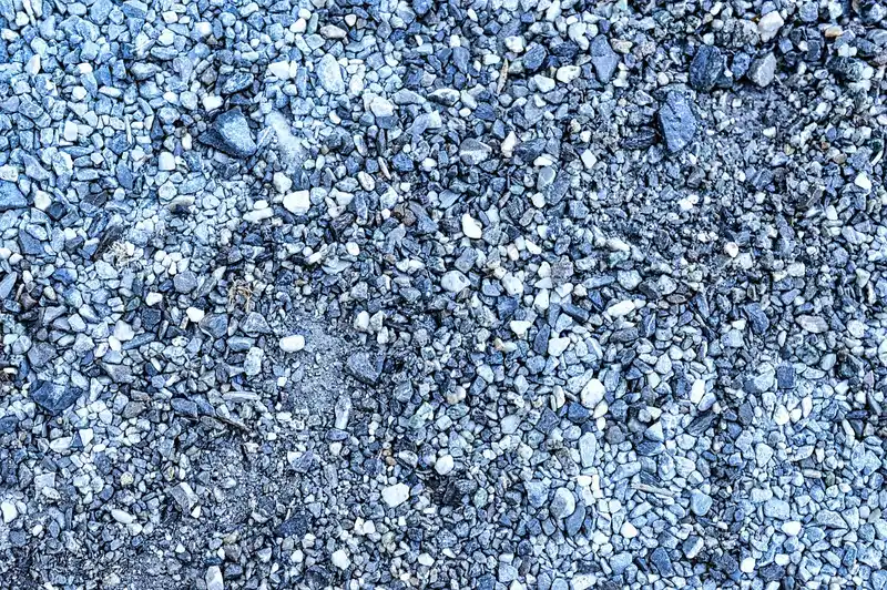 Backyard soil prepared for gravel landscaping with a slope, shovel, and level in natural light