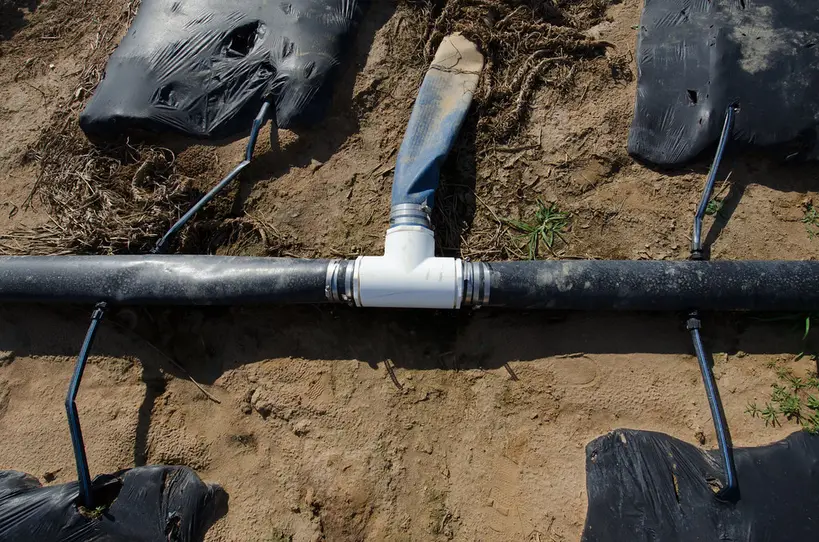 Close-up of a pressure regulator being checked on drip tubing with a wrench