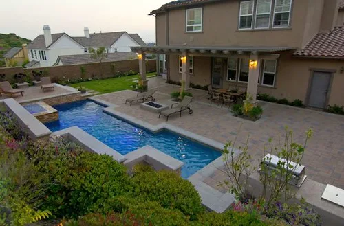 Landscaping services for backyard upgrades with a homeowner and landscaper beside pavers, mulch, and edged lawn
